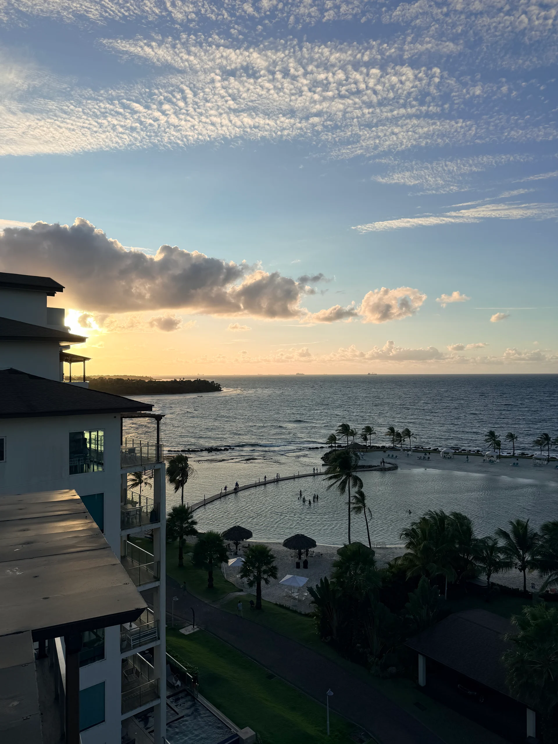 Vue imprenable au coucher du soleil sur les eaux calmes de Playa Escondida, Panama. La photo capture une magnifique vue sur l'océan avec une piscine à débordement incurvée au premier plan, encadrée par de luxuriantes palmiers et une architecture de station balnéaire moderne.