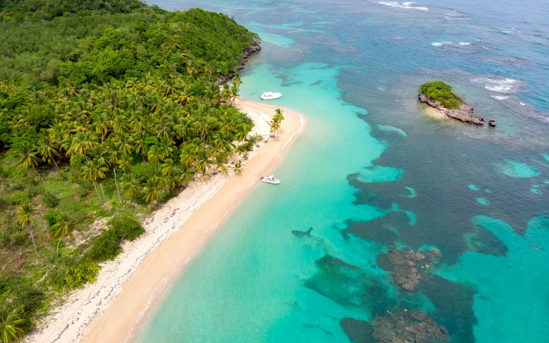 Vue aérienne époustouflante de Playa Escondida, une plage isolée à Panama, mettant en valeur des eaux turquoise, des sables immaculés et une végétation tropicale luxuriante. Deux bateaux glissent doucement le long du rivage, améliorant l'atmosphère idyllique et paisible.