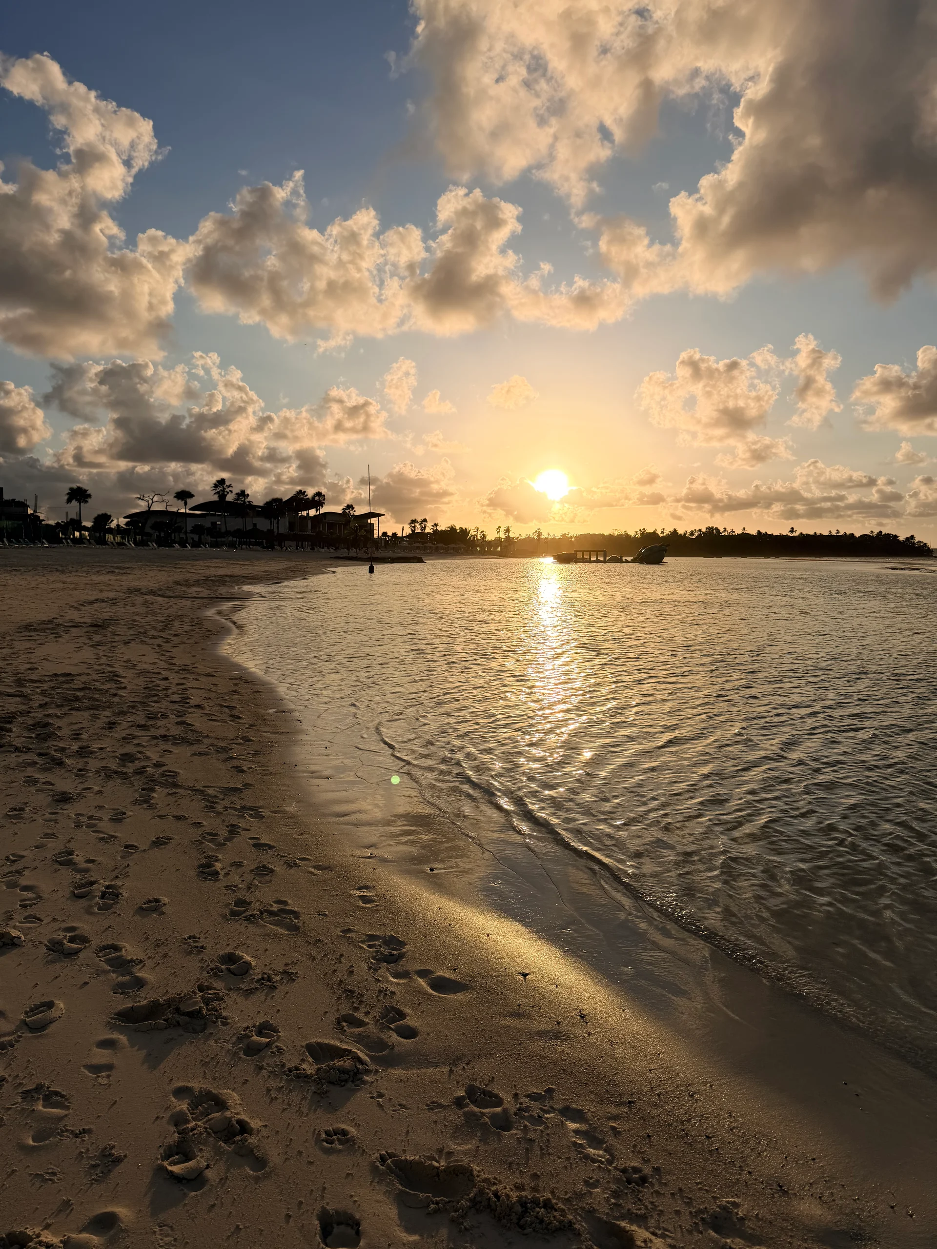 Un coucher de soleil époustouflant sur les eaux tranquilles de Playa Escondida, Panama. La lumière dorée se reflète sur le sable mouillé, créant une scène paisible et pittoresque avec des empreintes de pas menant vers le rivage.