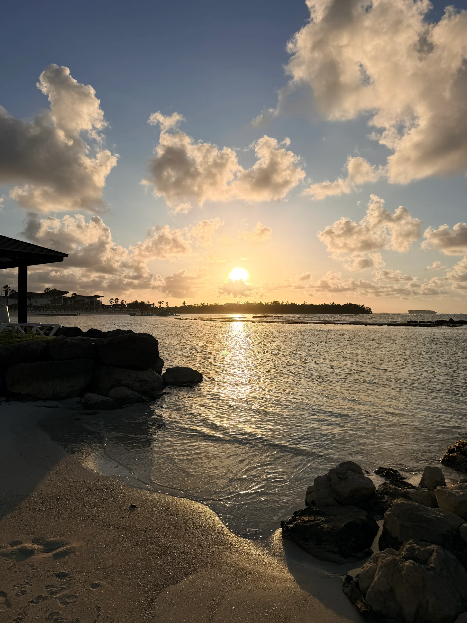 Une vue imprenable sur le coucher de soleil au-dessus de la mer des Caraïbes calme, capturée depuis un balcon surplombant Playa Escondida, au Panama. La lumière dorée se reflète sur l'eau, mettant en valeur la silhouette des palmiers et des îles voisines.