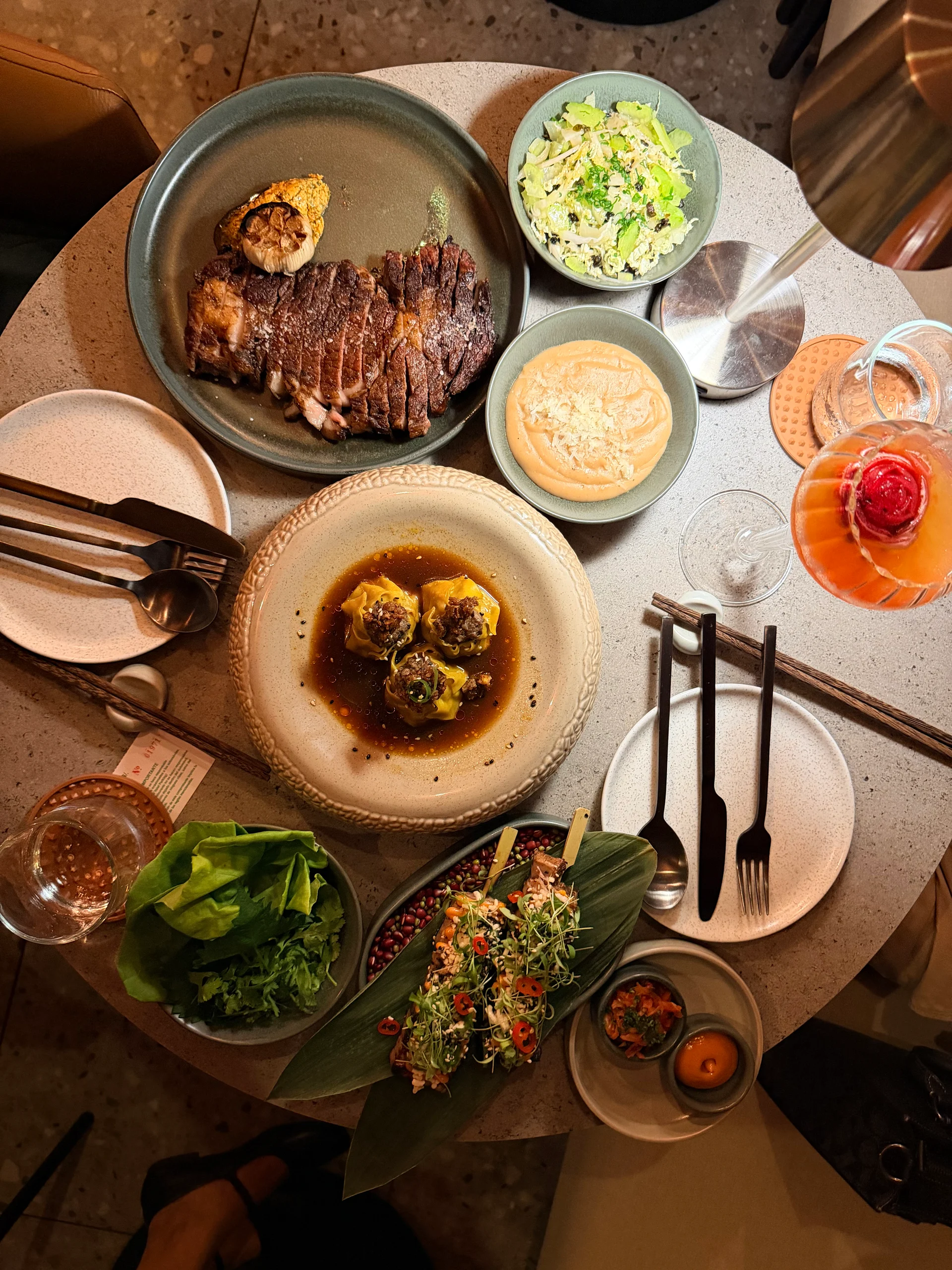 An overhead shot of a lavish dining experience at Dovle Cincuentenario, showcasing a variety of exquisitely plated dishes and refreshing cocktails. The table is beautifully set with elegant tableware, creating an inviting and luxurious atmosphere.