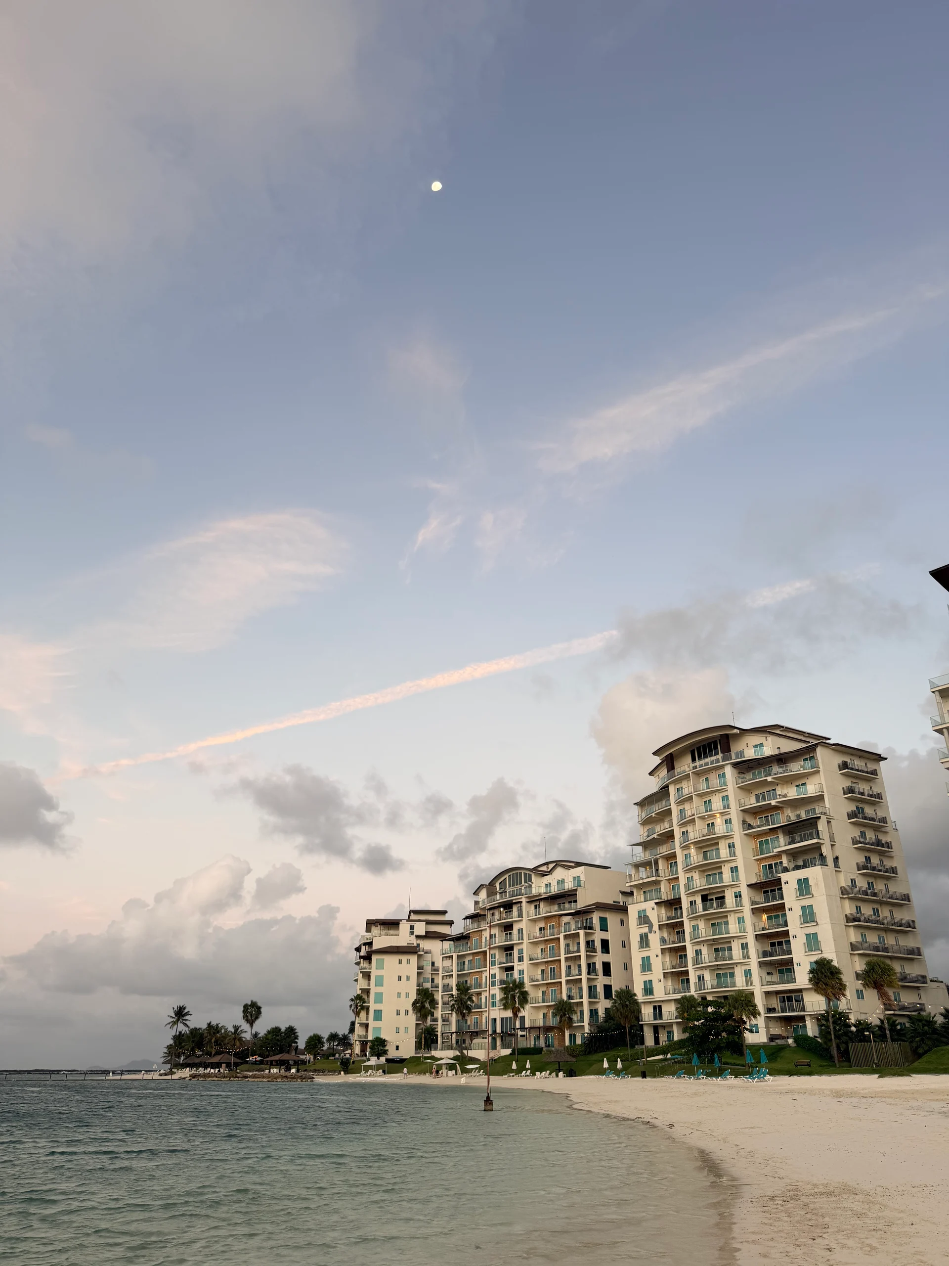 Une vue panoramique et sereine de Playa Escondida, Panama, mettant en valeur les bâtiments de plusieurs étages du resort sur fond de ciel nuageux et d'eaux turquoise calmes. La scène capture l'atmosphère tranquille de ce paradis des Caraïbes, idéale pour la détente et l'évasion.