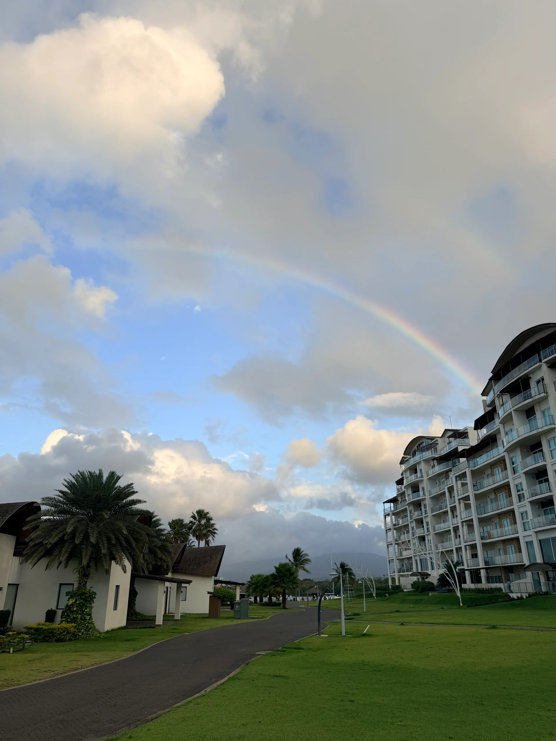 Un arc-en-ciel éclatant s'étend au-dessus des terrains du complexe hôtelier de Playa Escondida, en Panama, mettant en valeur la verdure luxuriante et l'architecture moderne de la propriété. La scène évoque un sentiment de tranquillité et de beauté naturelle, parfaite pour capturer l'essence d'une escapade tropicale.